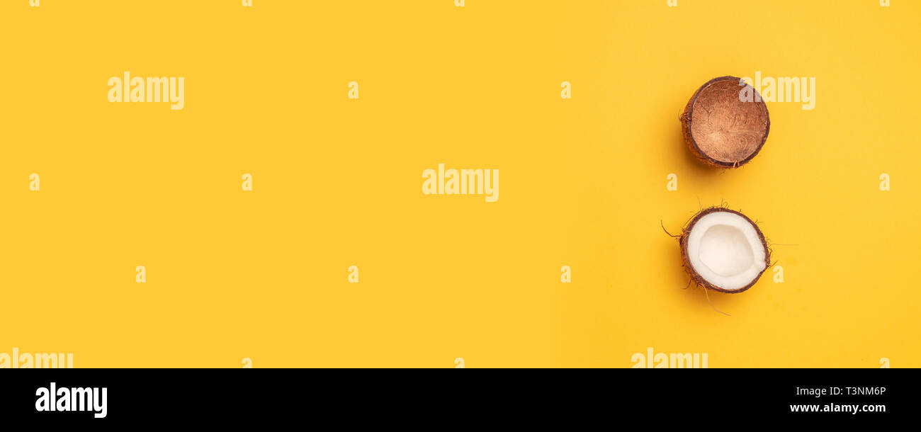 Organische frische zwei Stücke der Kokosnuss auf einem gelben Hintergrund. Flach Stockfoto