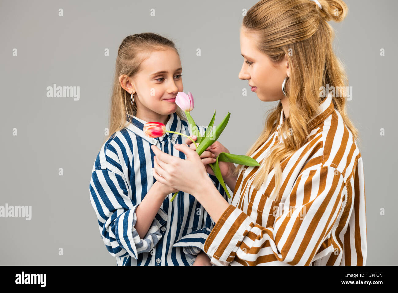 Langhaarige einwandfreie Damen in helle Kleidung teilen Blumen Stockfoto