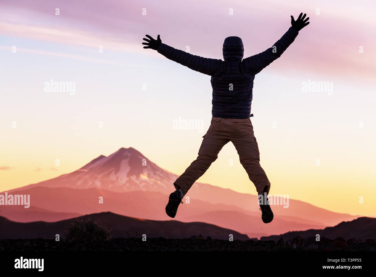 Springen Mann in die hohen Berge bei Sonnenuntergang Stockfoto