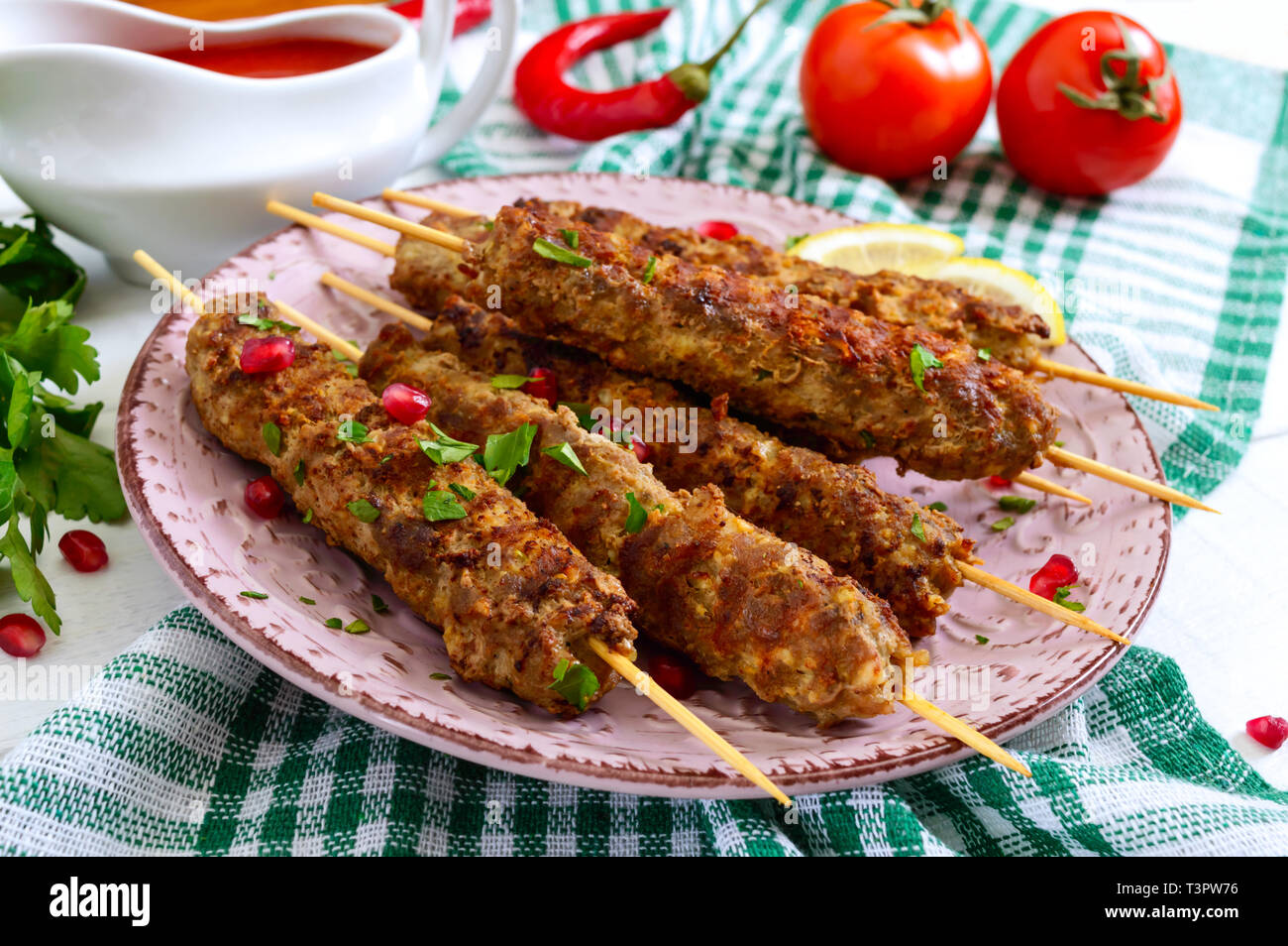 Lecker lula Kebab auf der Platte auf einem weißen Holztisch. Gehacktes Fleisch auf Holzspieße, gegrillt. Östliche Küche. Stockfoto
