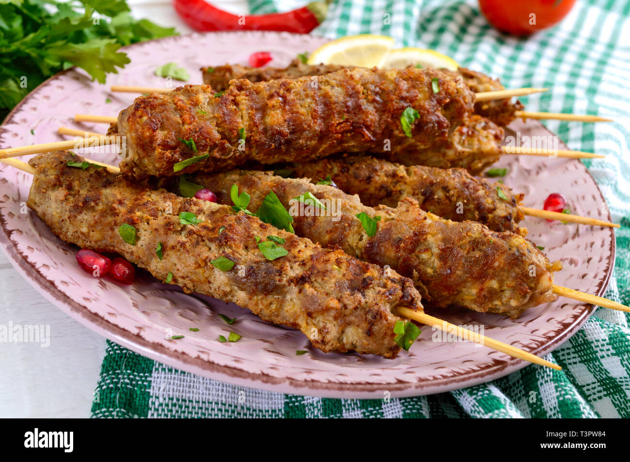 Lecker lula Kebab auf der Platte auf einem weißen Holztisch. Gehacktes Fleisch auf Holzspieße, gegrillt. Östliche Küche. Stockfoto