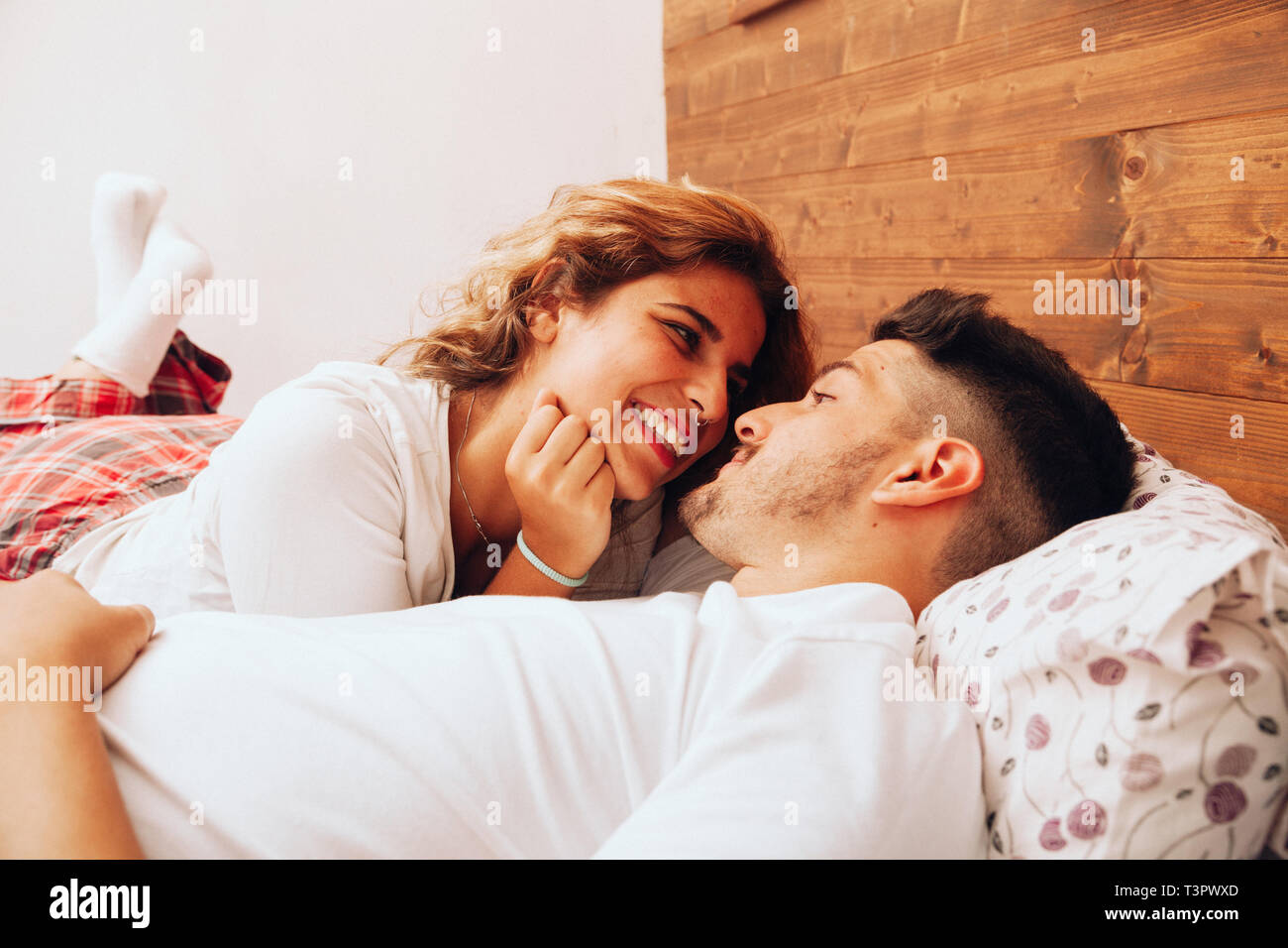 Junge lächelnde heterosexuellen Paaren, die zusammen auf dem Bett liegend Stockfoto