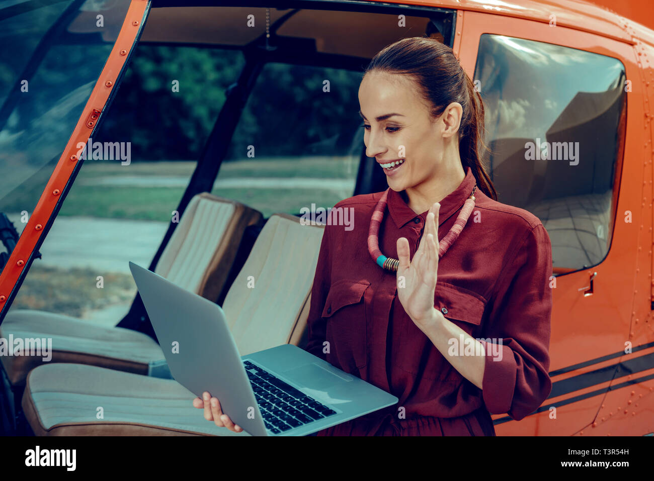 Gut - Zufrieden aussehende Frau mit gebunden Haar winkte ihr Haar und Begrüßung Stockfoto