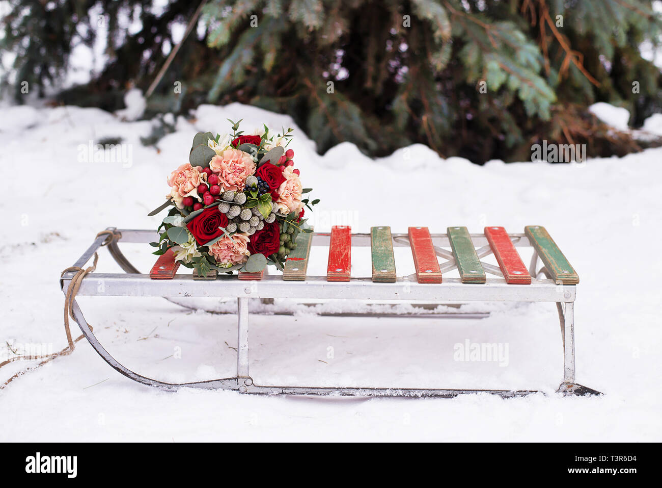 Schönen Brautstrauß liegt auf einem Schlitten für Winter auf weißen Schnee in einer verschneiten Park Stockfoto