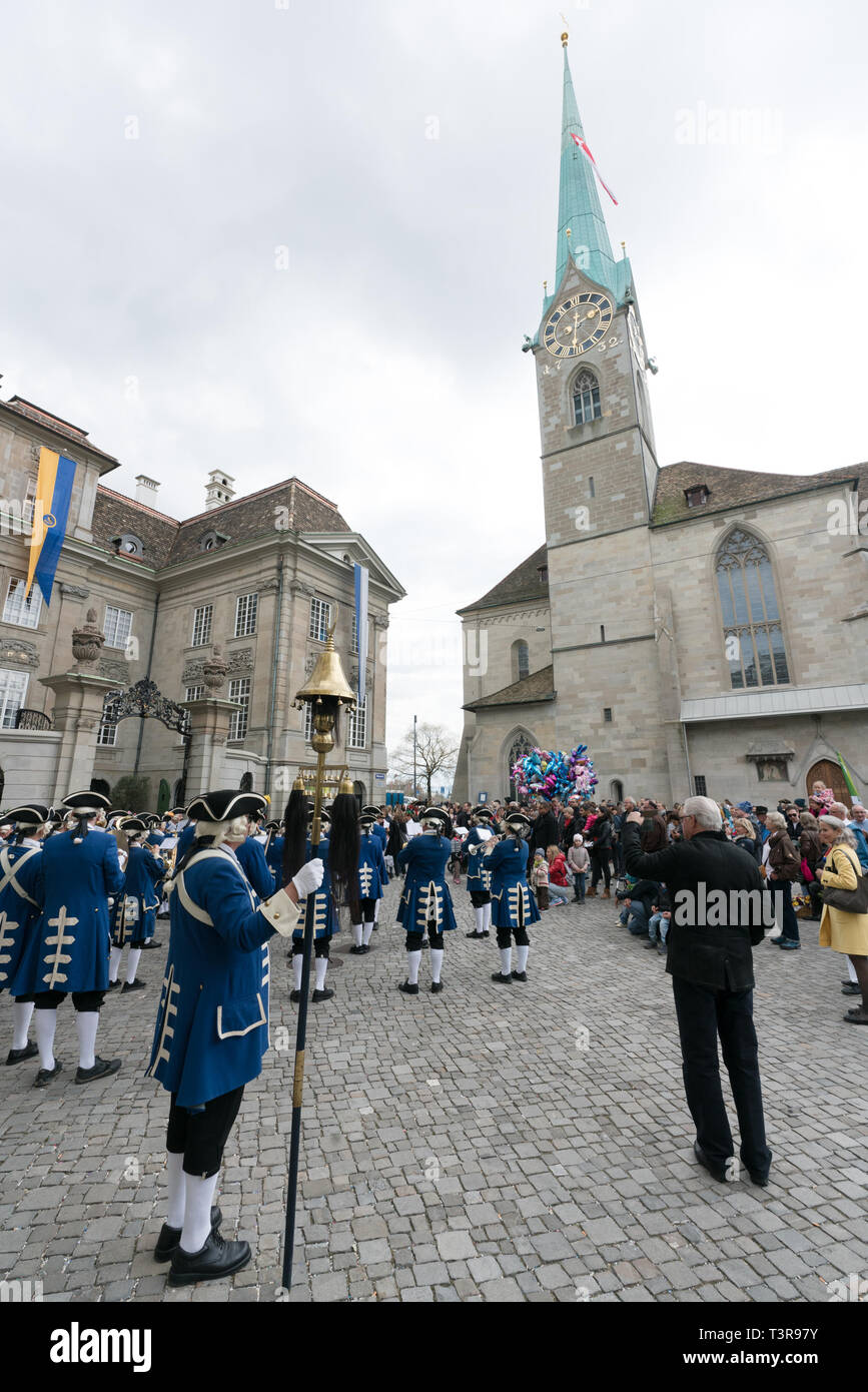 Zürich, ZH/Schweiz - April 8, 2019: Das traditionelle Frühlingsfest der Sechselaeuten in Zürich mit Menschen neben einer marching band feiern. Stockfoto