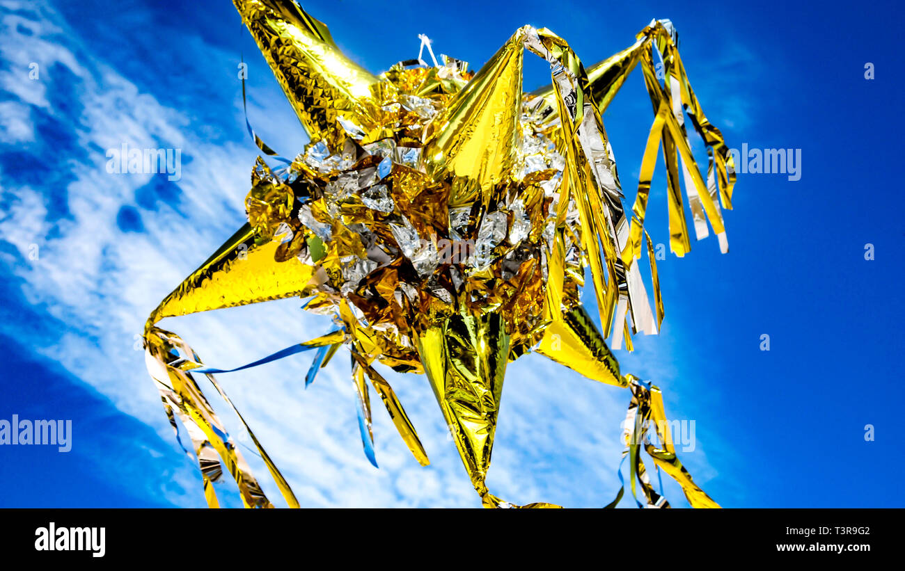 Große bunte Gold und Silber Mexikanische peñata vor einem blauen Himmel mit weißen Wolken, Schuß an einem schönen Tag in Mexiko Stockfoto