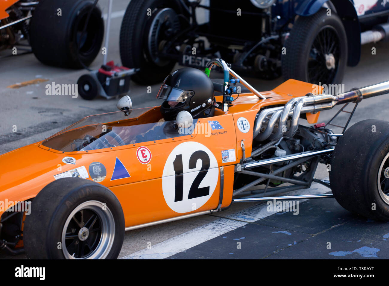 Close-up von Steve Weller im Cockpit seiner orange, 1968 Sitzen, Elfin 600B historische Formel 2 Rennen auto, Am2019 Silverstone Classic Media Day Stockfoto