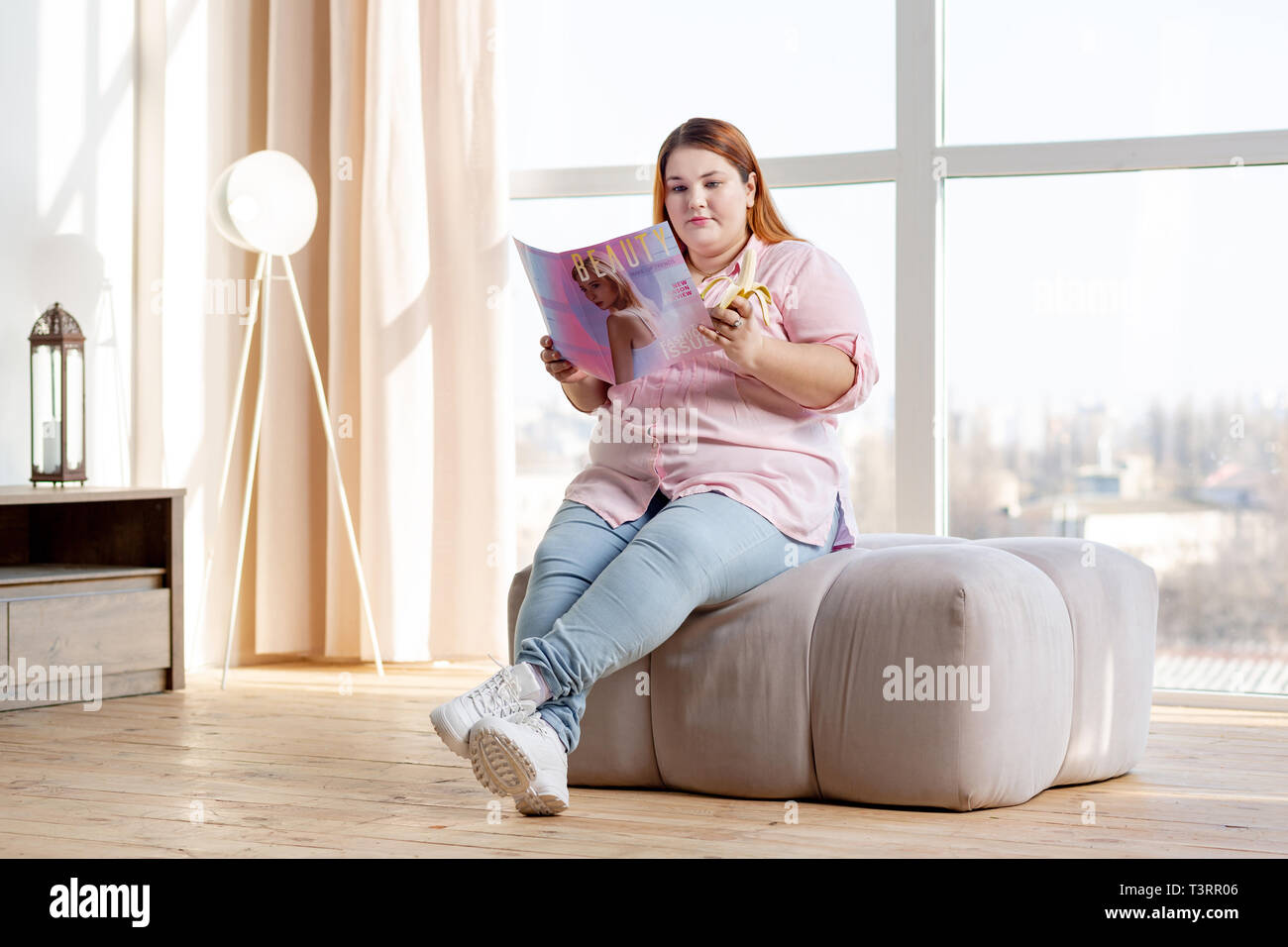 Angenehme übergewichtige Frau liest eine Zeitschrift zu Hause Stockfoto