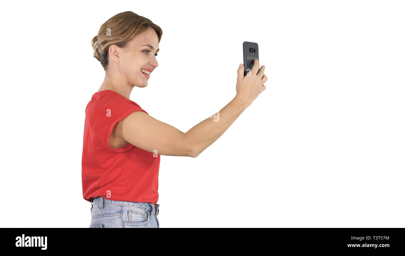 Schöne junge Frau zu Fuß und mit einem Smartphone Bilder und selfies auf weißem Hintergrund zu nehmen. Stockfoto