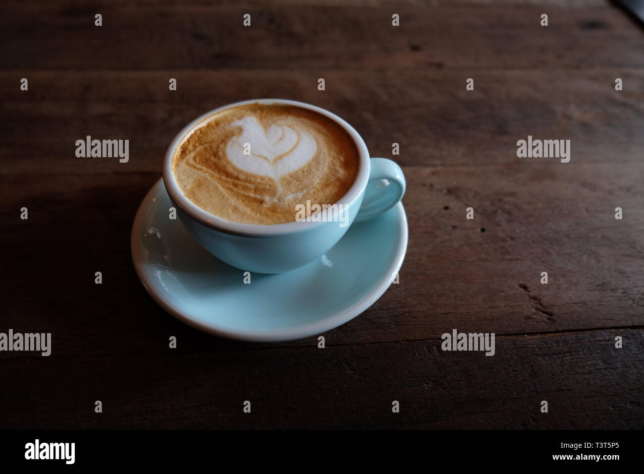 Cappuccino oder Latte mit aufgeschäumter Schaumstoff, blau Kaffeetasse oben auf hölzernen Coffee shop Hintergrund Stockfoto