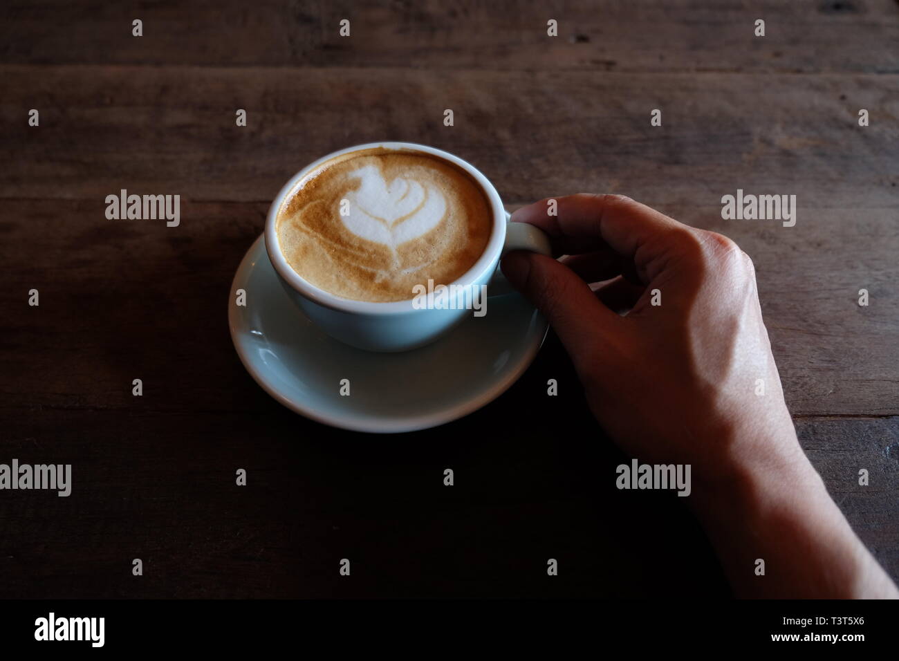 Hände, die heiße Tasse Kaffee auf rustikalen Holztisch Hintergrund Stockfoto