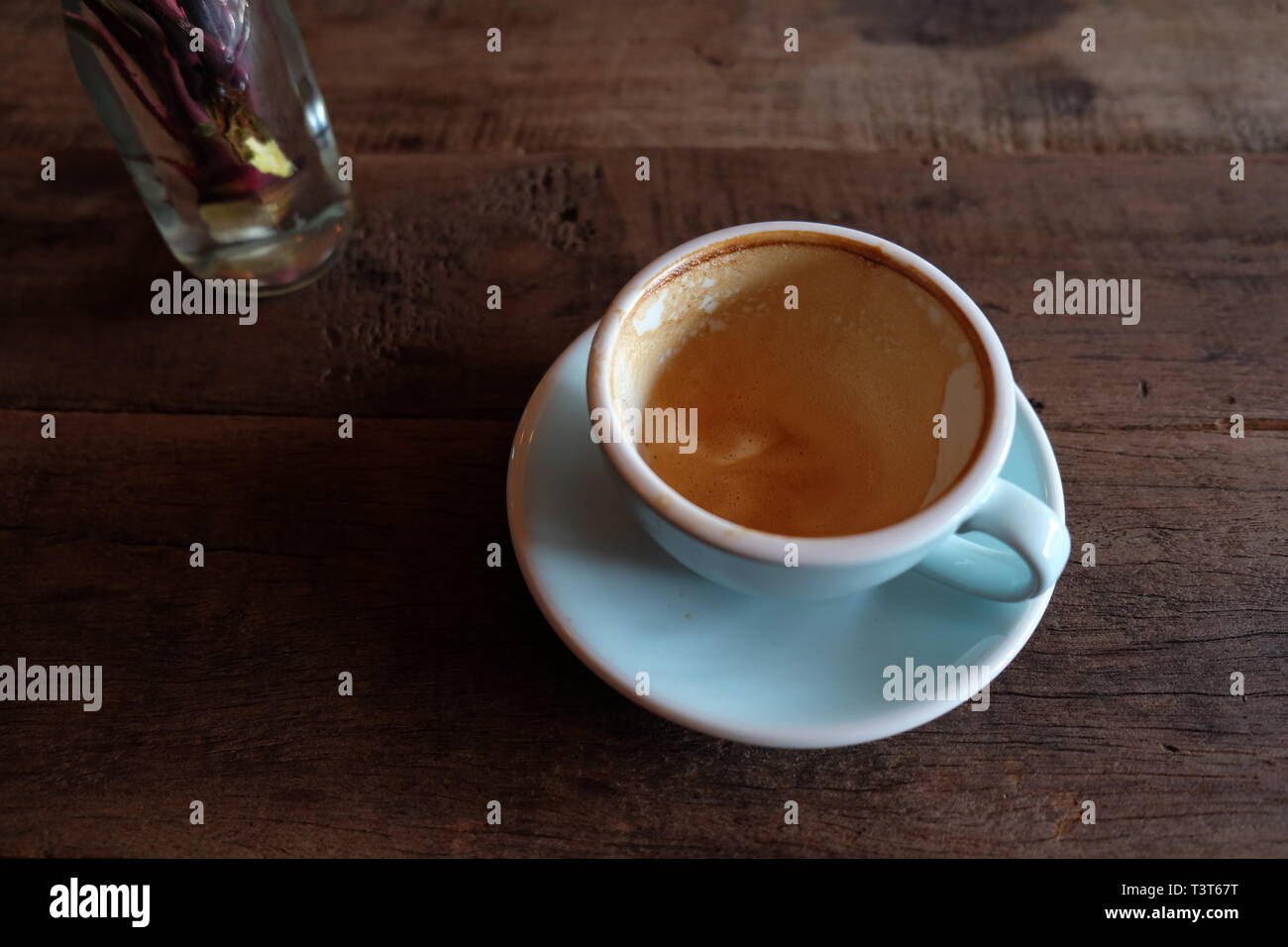 Cappuccino oder Latte mit aufgeschäumter Schaumstoff, blau Kaffeetasse oben auf hölzernen Coffee shop Hintergrund Stockfoto