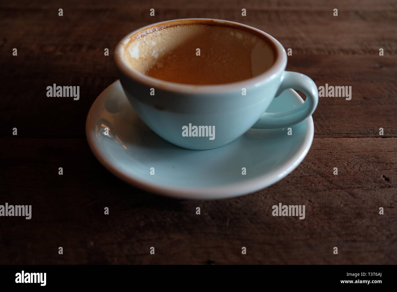 Cappuccino oder Latte mit aufgeschäumter Schaumstoff, blau Kaffeetasse oben auf hölzernen Coffee shop Hintergrund Stockfoto