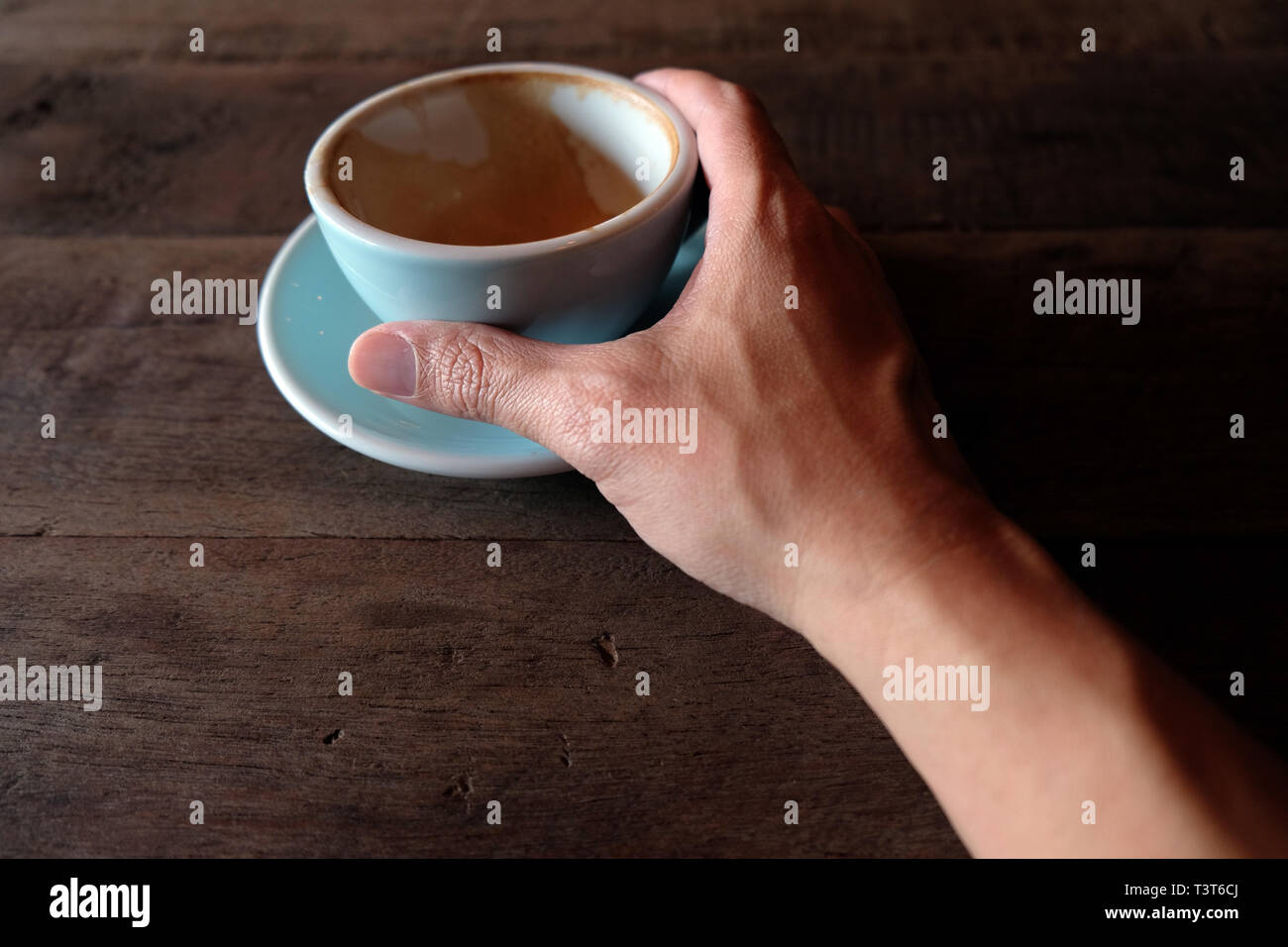 Hände, die heiße Tasse Kaffee auf rustikalen Holztisch Hintergrund Stockfoto