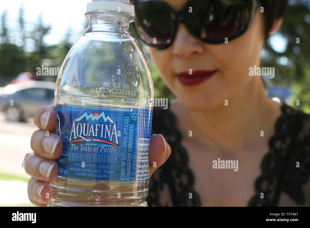 Schöne dunkelhaarige Mädchen auf einem hellen, sonnigen Tag im Park mit einem Drink von gereinigtem Wasser. Stockfoto
