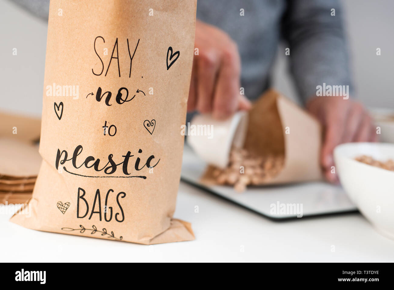 Nahaufnahme von einem kaukasischen Mann einige trockene Kichererbsen auf braunem Papier Kegel, auf einer elektronischen Waage gelegt, und eine Papiertüte in den Vordergrund mit dem Stockfoto