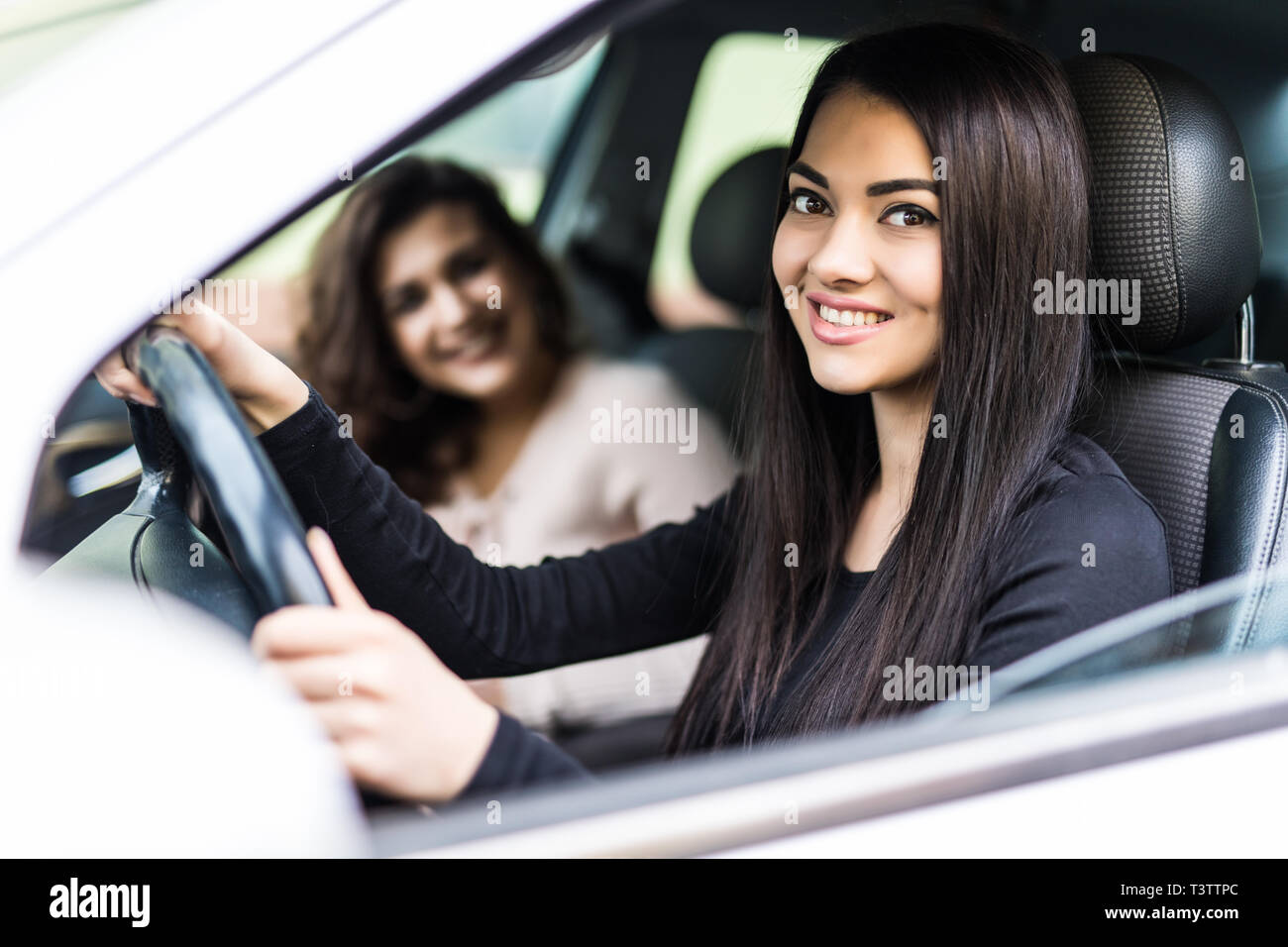 Zwei freundliche junge Frauen genießen Sie einen Tagesausflug in die Stadt gesehen durch das offene Fenster des Autos glücklich in die Kamera grinsend Stockfoto