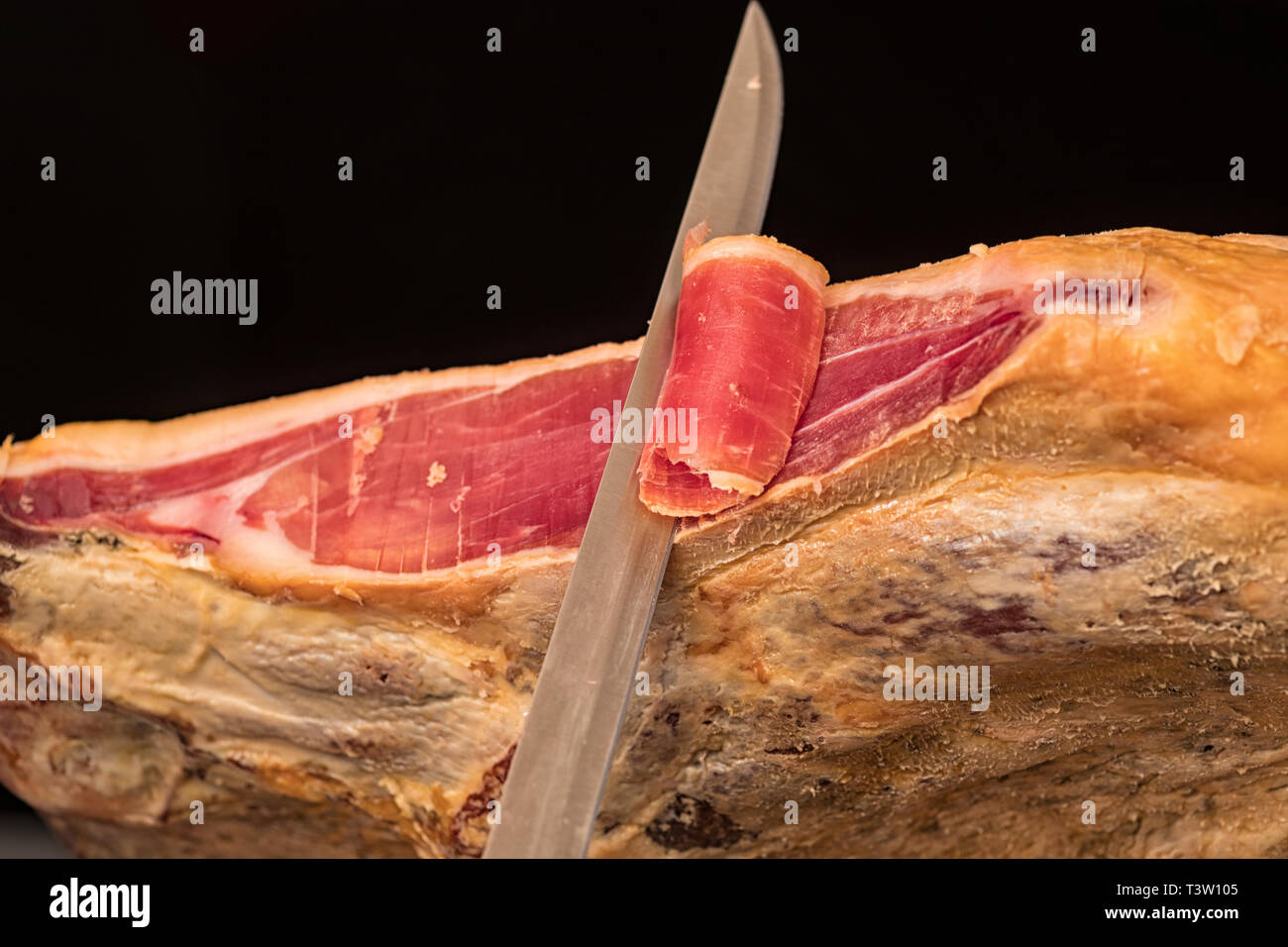 Nahaufnahme eines Messers Schneide ein spanischer Serrano Schinken Stockfoto