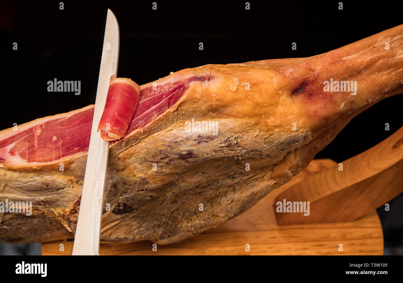 Nahaufnahme eines Messers Schneide ein spanischer Serrano Schinken Stockfoto