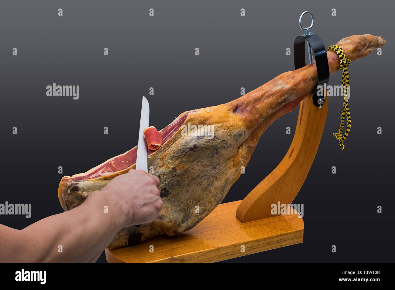 Hand schneidet mit dem Messer an einer spanischen Serrano Schinken in einem Holz-Halter - isoliert Stockfoto
