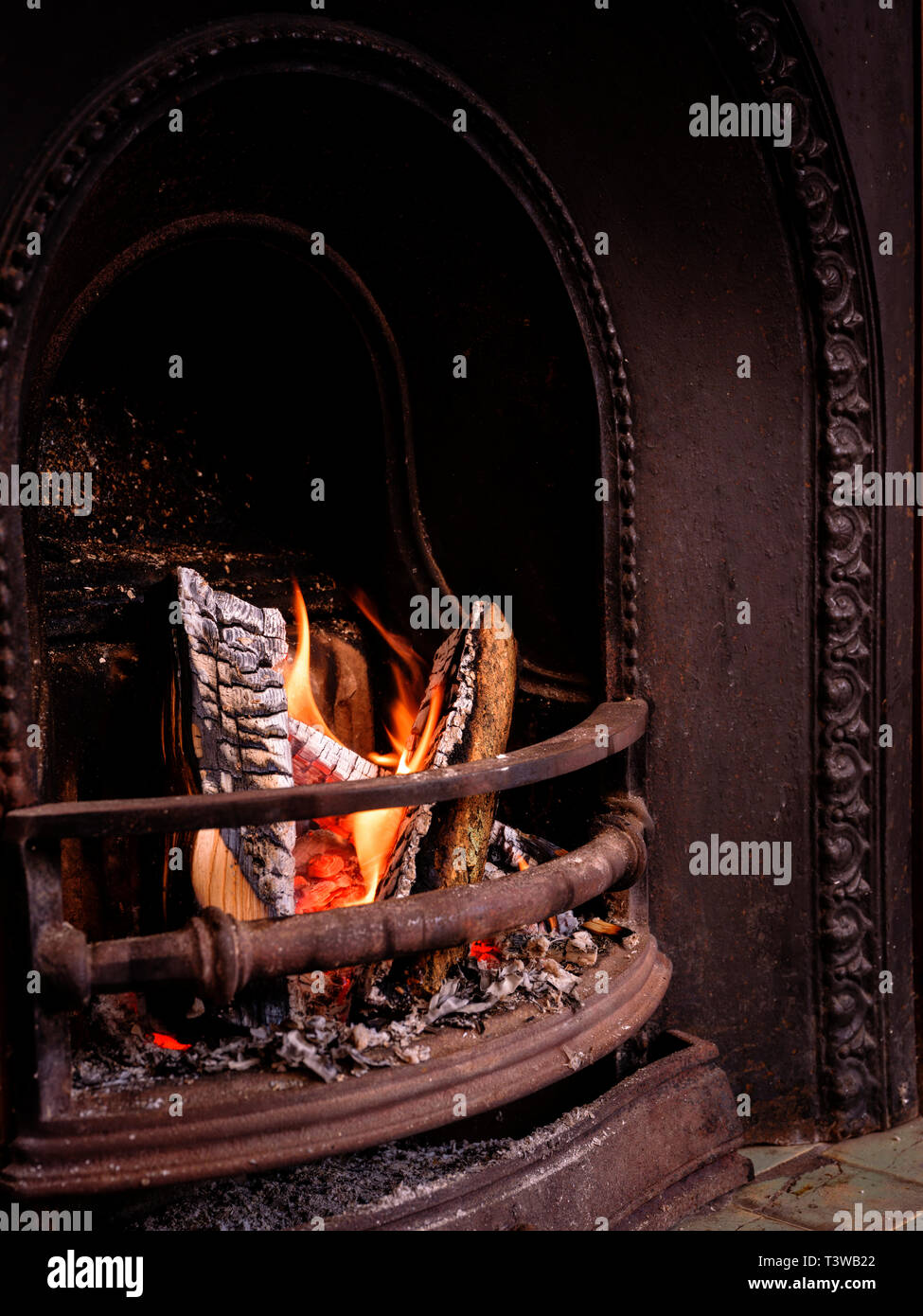 Ein offenes Feuer mit teilweise verbrannte Protokolle in einem viktorianischen Kamin. Stockfoto