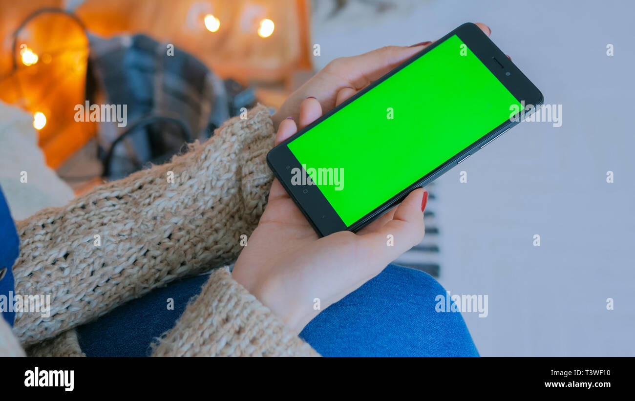 Frau auf der Suche nach smart phone Telefon mit Green Screen Stockfoto