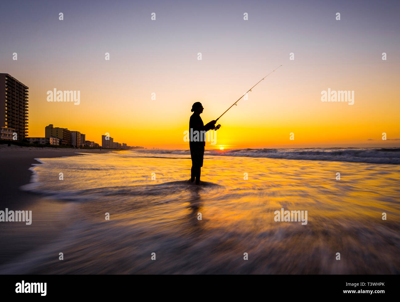 Unscharfen Blick auf Silhouette der Mann Angeln in Wellen am Strand bei Sonnenuntergang Stockfoto