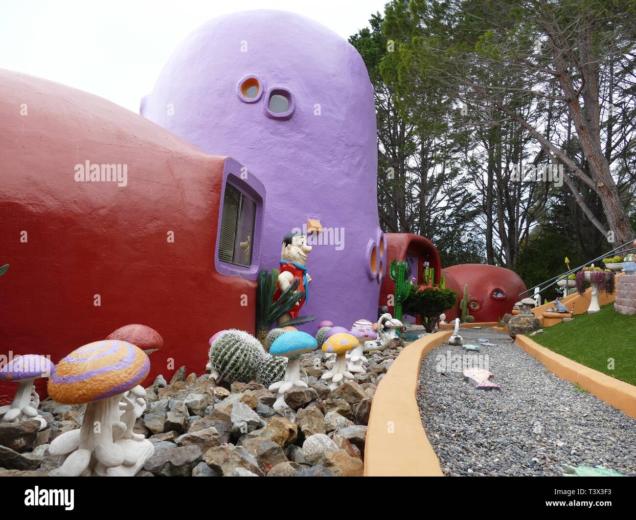 Hillsborough, USA. 11 Apr, 2019. Eine Abbildung von Fred Feuerstein (Fred Flintstone) steht vor einem bunt bemalten Haus in einer ungewöhnlichen Stil in Hillsborough, in der Nähe von San Francisco. Ein Kalifornier ihre ungewöhnliche Flintstone House mit Meter hohen Dinosaurier und anderer Figuren geschmückt. Für einige Vertreter der Stadt in diesem phantastischen Ort, es ist ein Blot. Jetzt den Bau Streit vor Gericht zu gehen. Quelle: Barbara Munker/dpa/Alamy leben Nachrichten Stockfoto