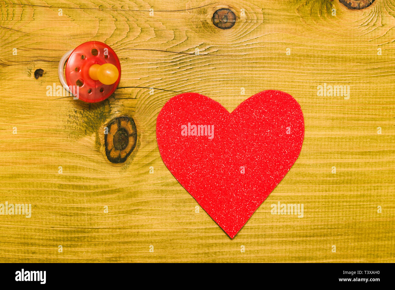 Rosa Schnuller für Baby Girl mit Herz Form auf Holztisch. Baby Ankündigung Konzept. Getönten Foto. Stockfoto