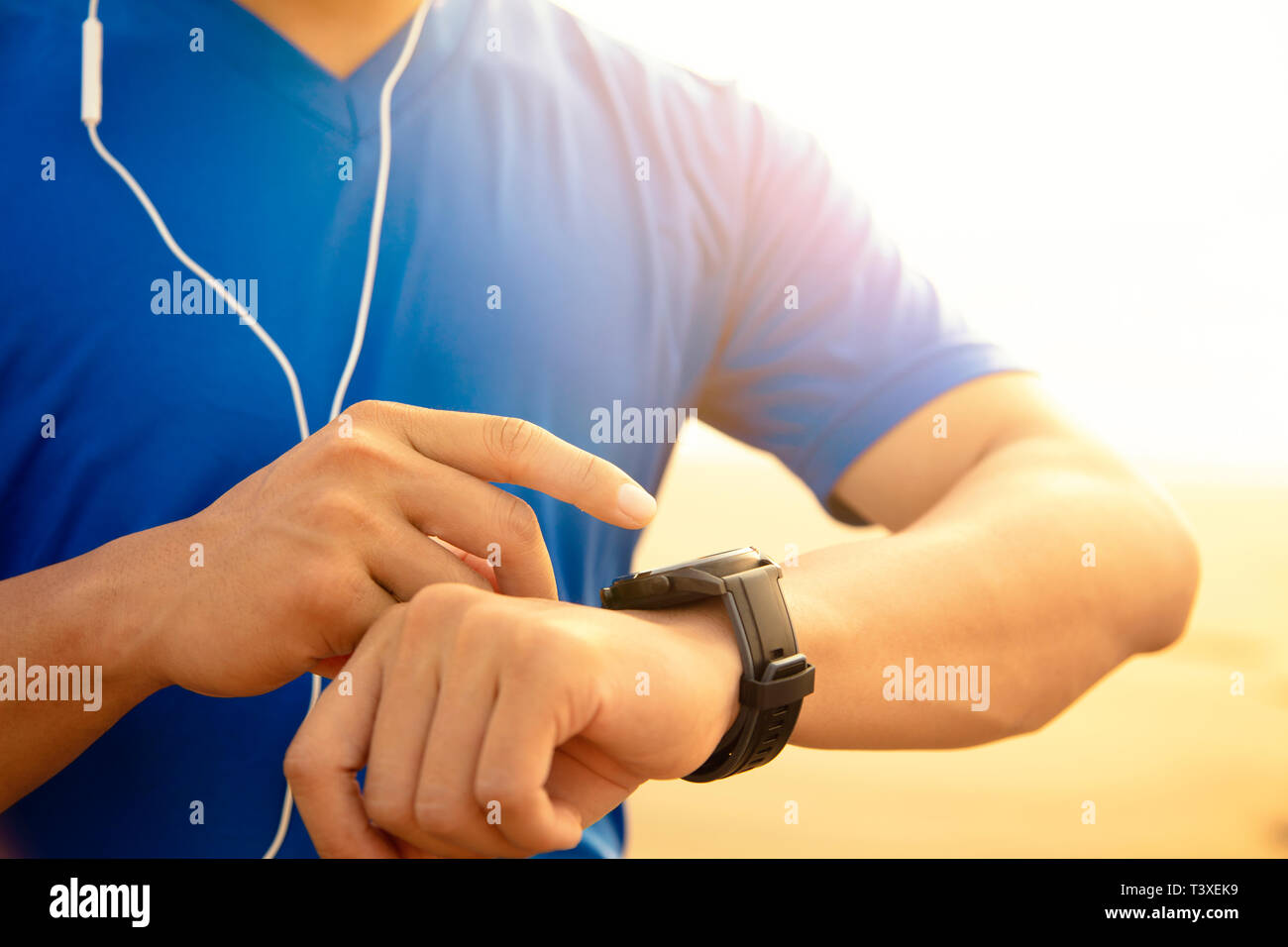 Junge Mann laufen am Strand und Kontrolle der Herzfrequenz auf Watch Stockfoto