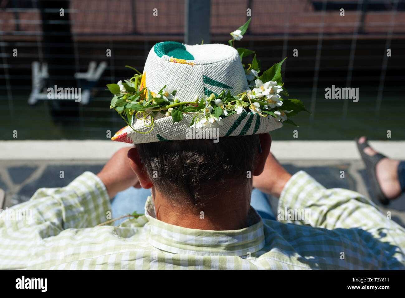 23.06.2018, Helsinki, Finnland, Europa - ein Mann, der eine Blume dekoriert Hut sitzt durch den Allas Meer Pool. Anlässlich der Hochsommer viele Mitarbeiter Stockfoto