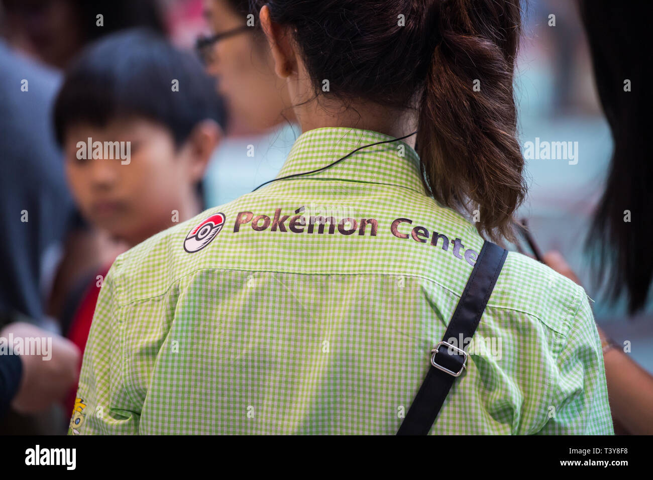 Rückansicht einer weiblichen Mitarbeiterin trägt Pokemon-Hemd mit Mittelkragen bei der Arbeit, Jewel Changi Airport, Singapur. Stockfoto