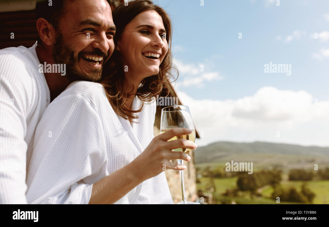 Nahaufnahme von einem lächelnden Paar im Urlaub gemeinsam auf dem Balkon von einem Haus auf dem Land. Lächelnde Frau mit einem Glas Weißwein wi Stockfoto