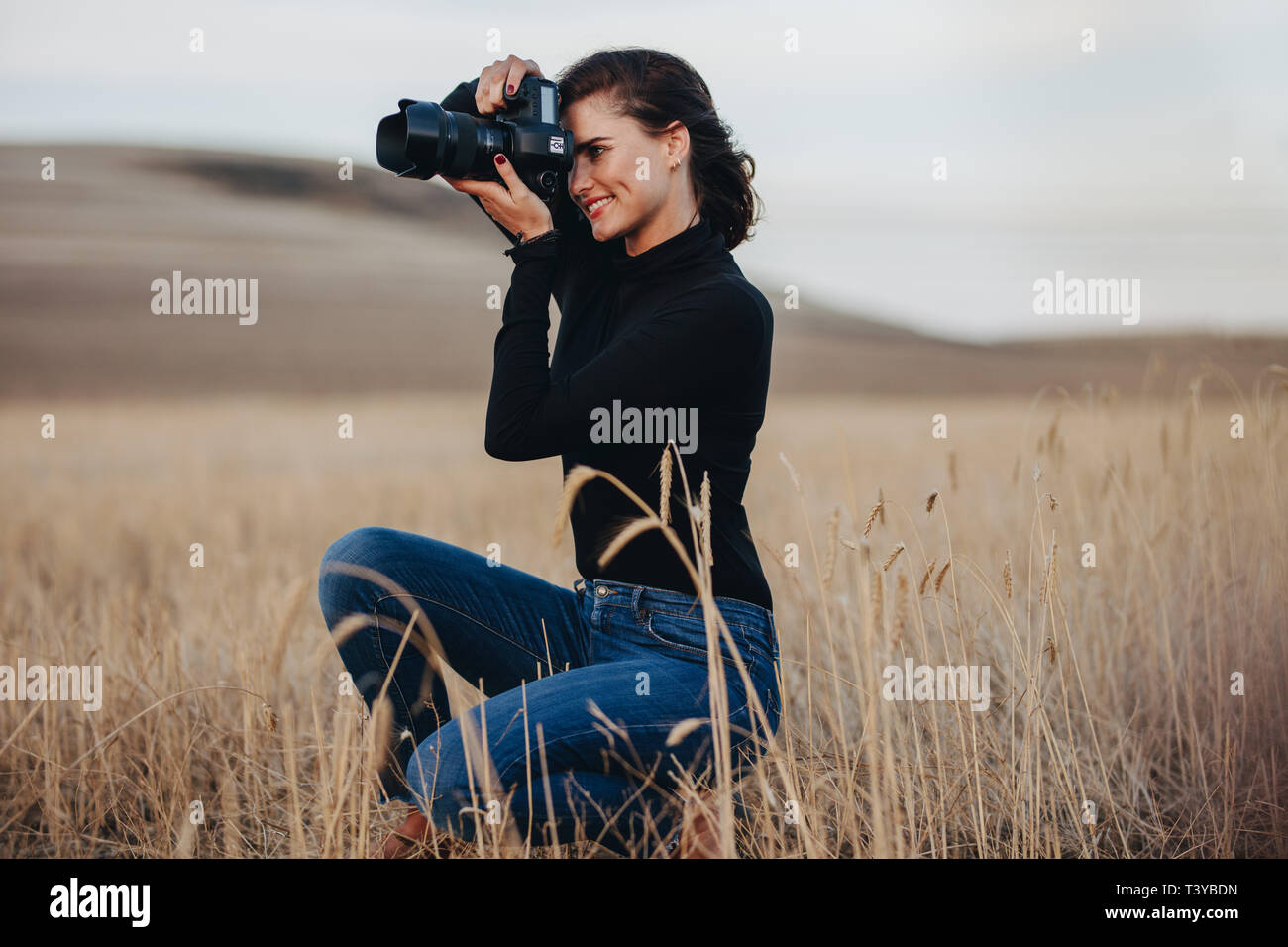 Junge Frau mit DSLR-Kamera für Aufnahmen im Freien. Weiblichen professionellen Fotografen Fotografieren mit einer DSLR-Kamera. Stockfoto