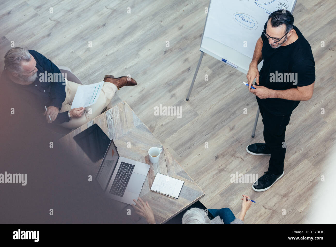 Reifen Geschäftsmann seine Ideen präsentieren auf dem Whiteboard zu Kollegen. Manager eine Präsentation halten, um seine Mannschaft im Konferenzraum im Büro. Stockfoto