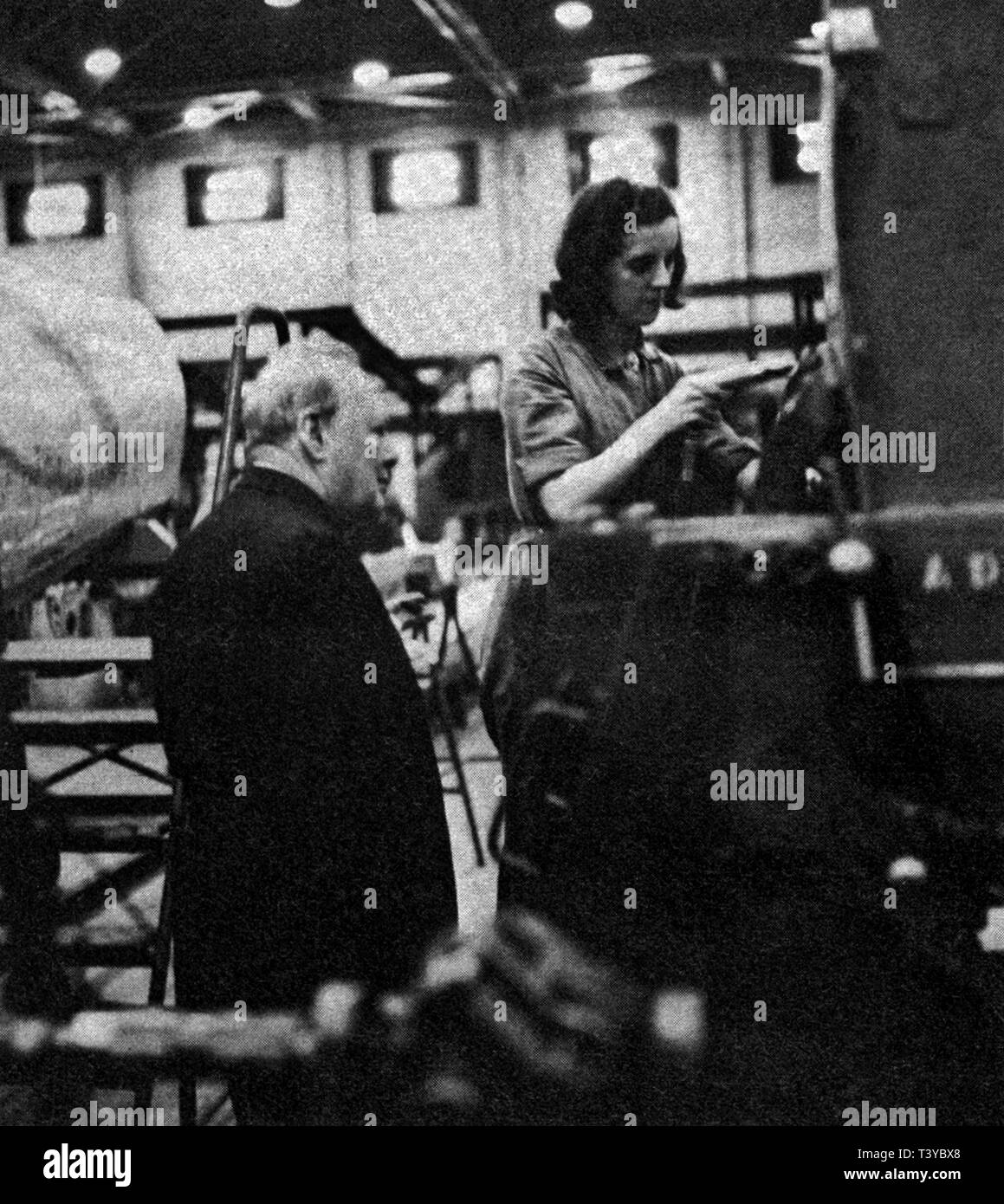 Winston Churchill beobachtet ein Mädchen, das an einem Spitfire in der Castle Bromwich Fabrik in der Nähe von Birmingham arbeitet. September 1941 Stockfoto