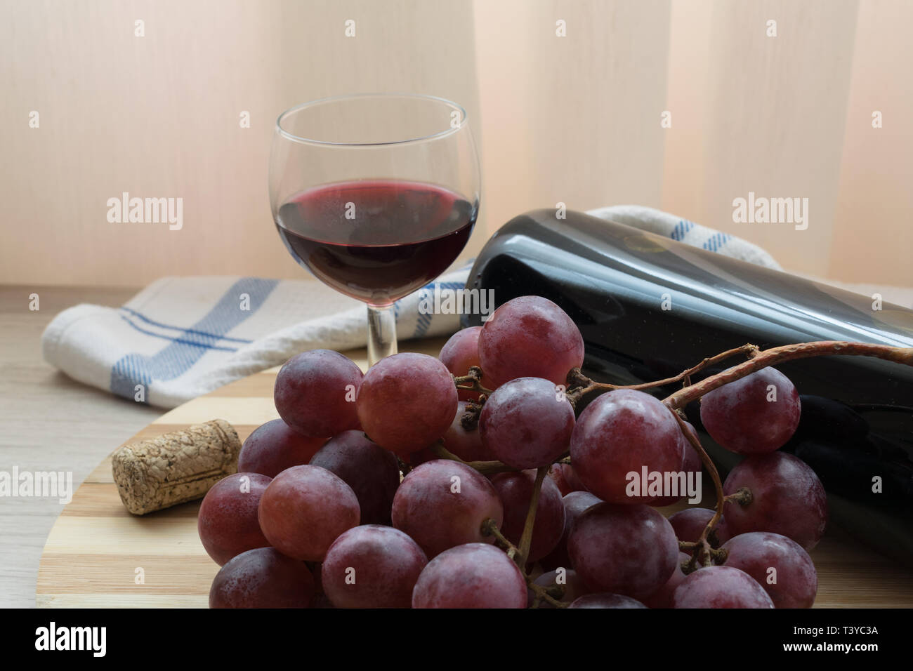 Rotwein in ein Glas mit ein paar Trauben und eine Flasche Stockfoto