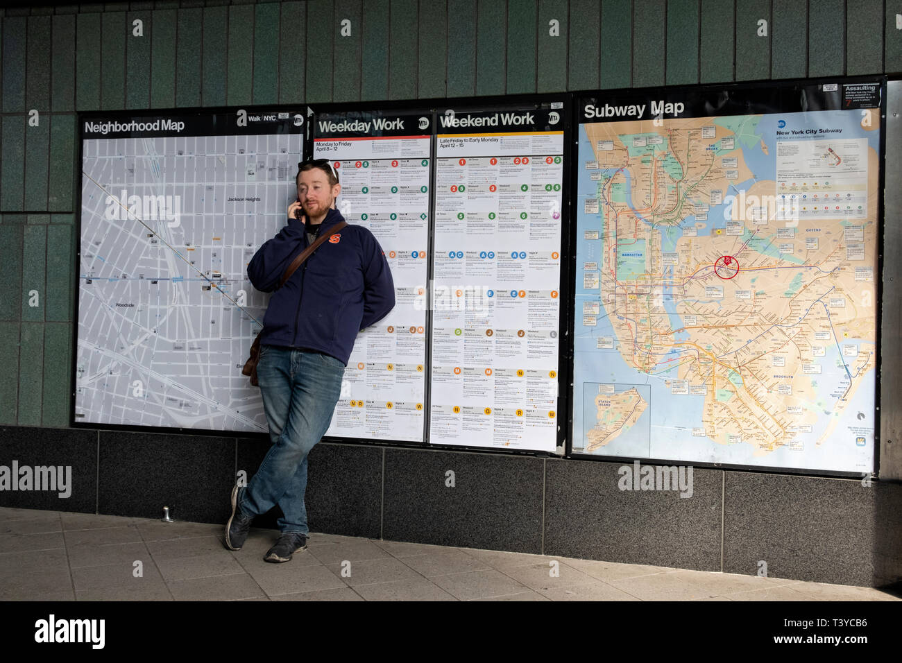 Ein junger Mann spricht über sein Mobiltelefon außerhalb des Roosevelt Ave-Jackson Höhen U-Bahn Station in Queens, New York City. Stockfoto