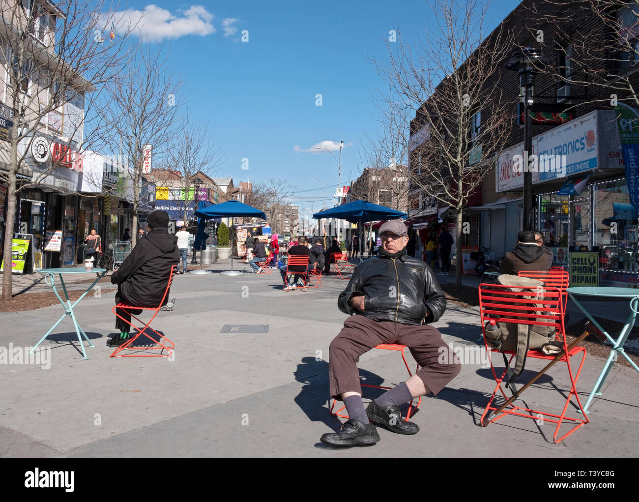 Ein alter Mann sitzt in einem öffentlichen Raum auf 37th Straße in Jackson Heights, Queens, New York City. Stockfoto