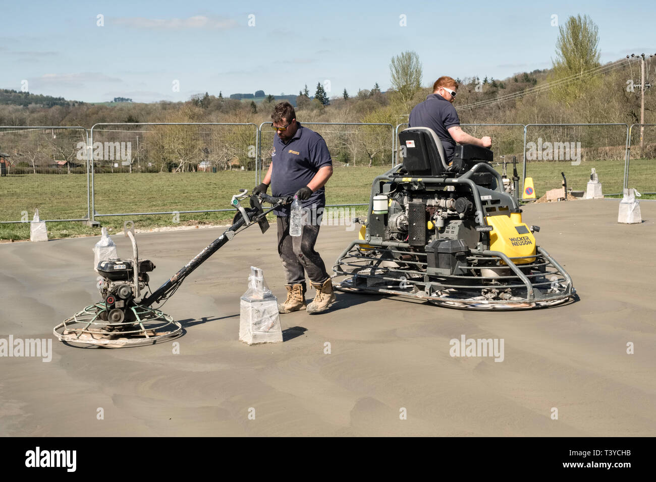 Presteigne, Powys, Wales, UK. Männer mit macht Kellen (power Floats) die Oberfläche eines frisch gelegte Betonplatte Stock zu glätten Stockfoto