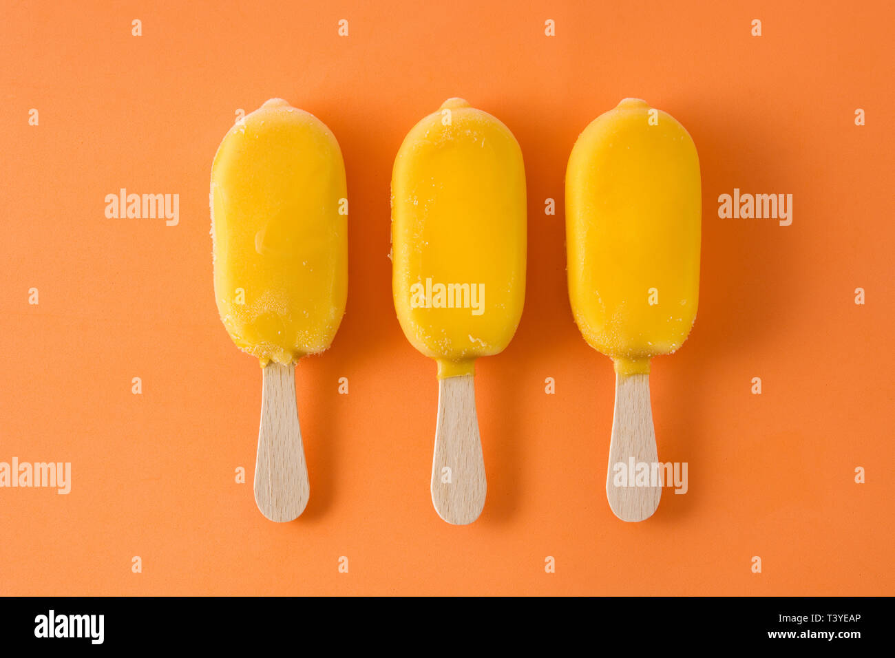 Orange Eis am Stiel Muster auf orangem Hintergrund. Ansicht von oben Stockfoto
