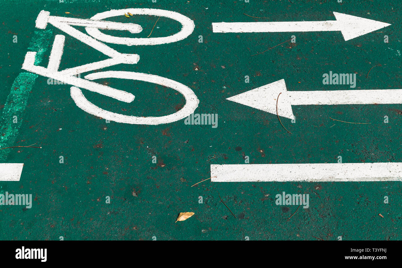 Rad weg, Straße Markierung mit Pfeilen und Bike Symbole über grüne Straße Stockfoto