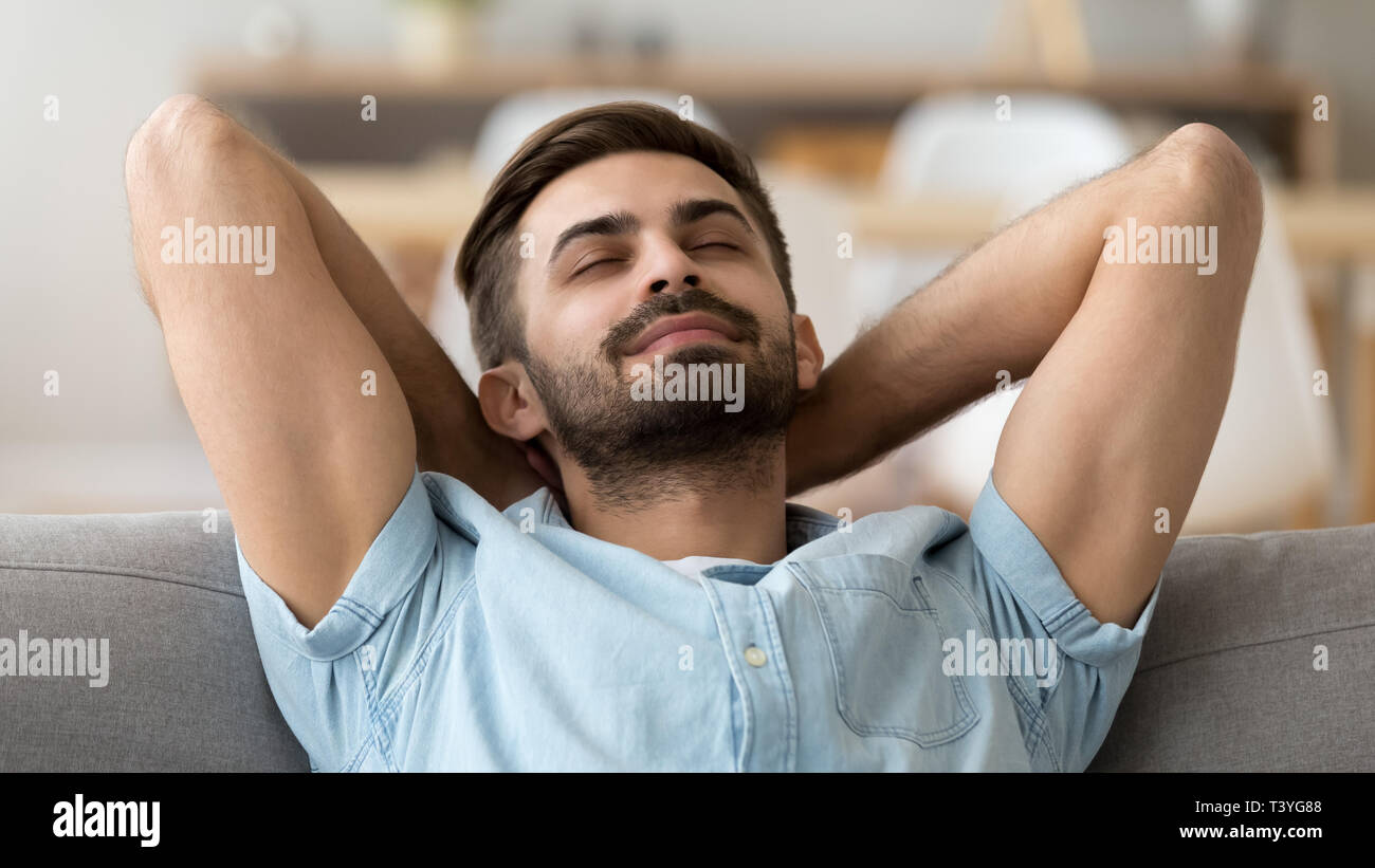 Ruhiger friedlicher Mann entspannt mit geschlossenen Augen lehnte sich zurück auf dem Sofa Stockfoto