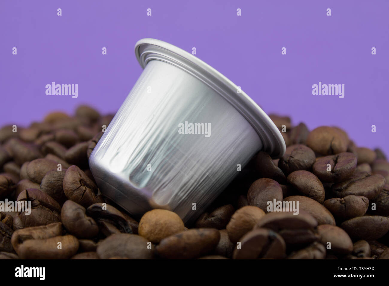Espresso Kapsel oder kaffeepad auf Kaffeebohnen, violetten Hintergrund. Kapseln für die Kaffeemaschine. Stockfoto