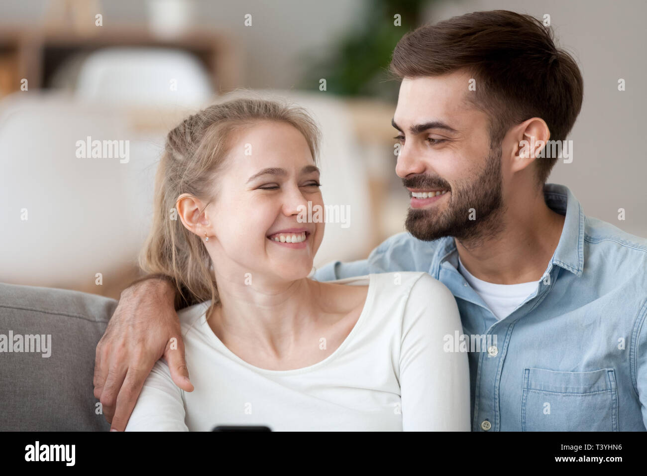 Glücklich lächelnde Mann und Frau kuscheln, mit Phone zusammen Stockfoto