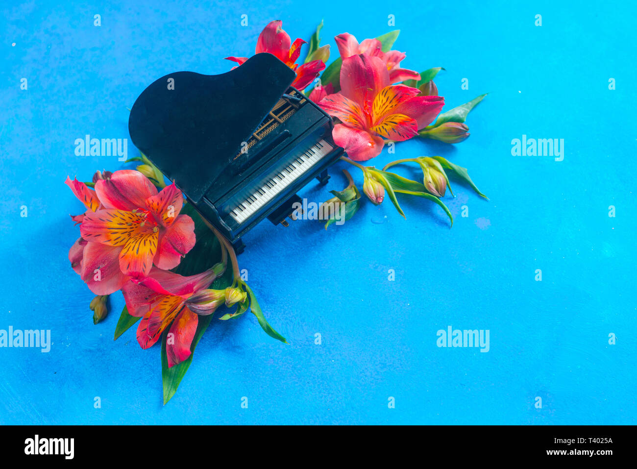 Kleine Piano mit Feder alstroemeria Blumen auf einem blauen Hintergrund mit kopieren. Frühling oder Sommer musikalische Festival Konzept mit Kopie Raum Stockfoto