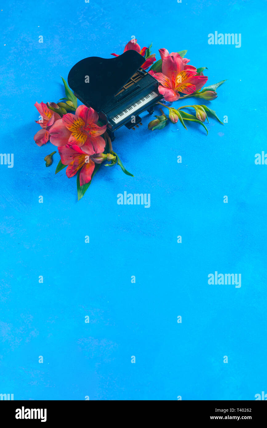 Kleine Piano mit Feder alstroemeria Blumen auf einem blauen Hintergrund mit kopieren. Frühling oder Sommer musikalische Festival Konzept mit Kopie Raum Stockfoto