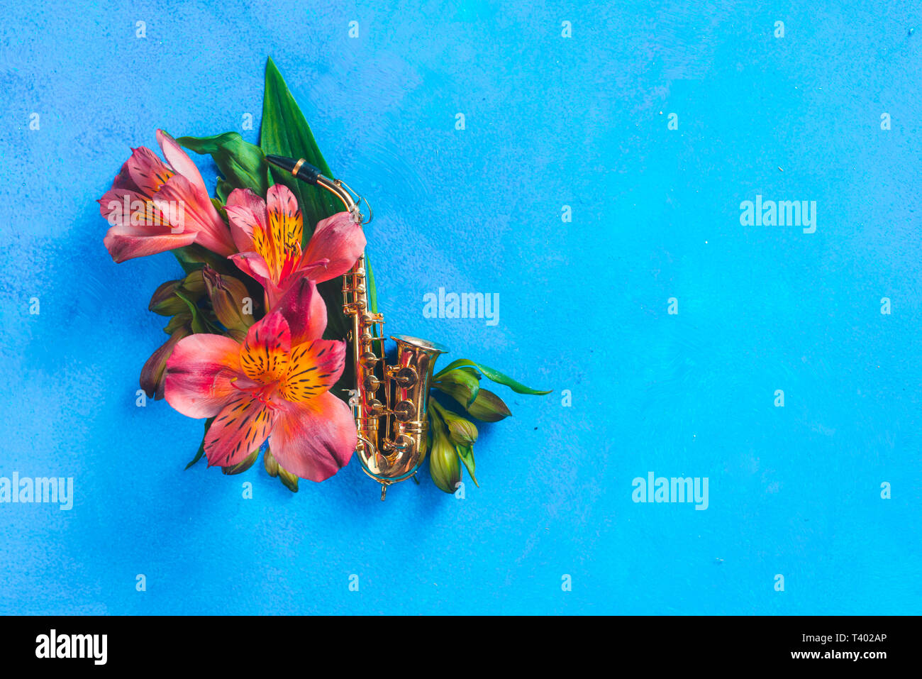 Winzige Saxophon mit Feder alstroemeria Blumen auf einem blauen Hintergrund mit kopieren. Frühling oder Sommer musikalische Festival Konzept mit Kopie Raum Stockfoto
