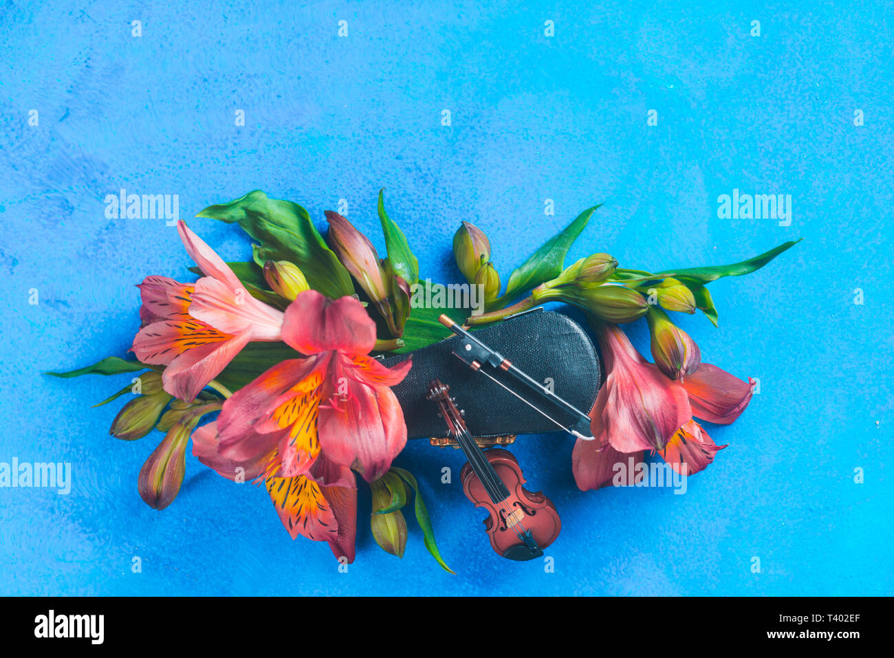 Kleine Geige mit Feder alstroemeria Blumen auf einem blauen Hintergrund mit kopieren. Frühling oder Sommer musikalische Festival Konzept mit Kopie Raum Stockfoto
