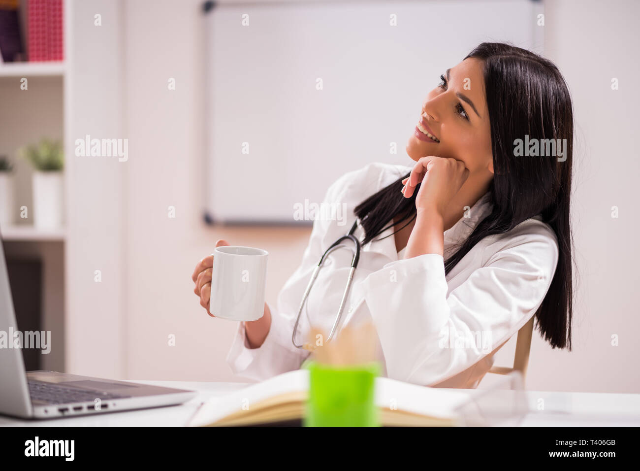 Junger Arzt trinkt Kaffee in Ihrem Büro. Stockfoto